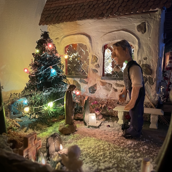 Jouluviikko. Kuvassa nukkekodin hautausmaa ja Eevert-nukke on sytyttämässä kynttilöitä