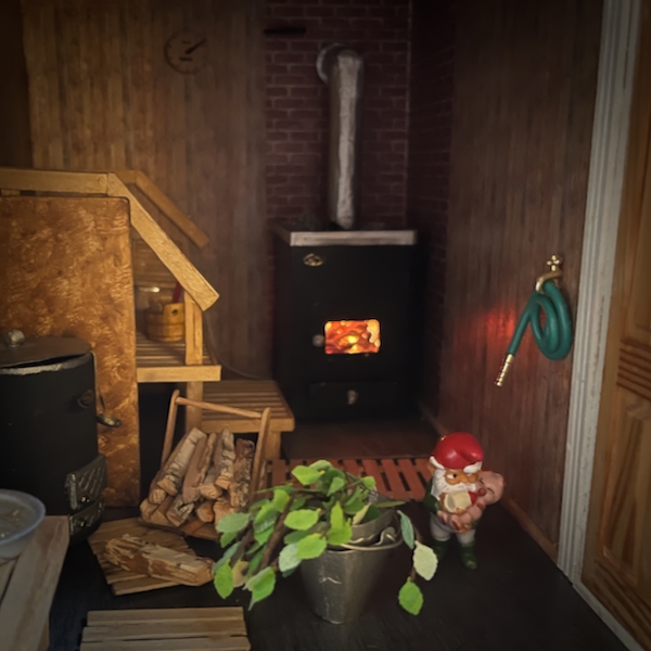Jouluviikko. Kuvassa nukkekodin sauna jonka kiukaassa on tuli. 