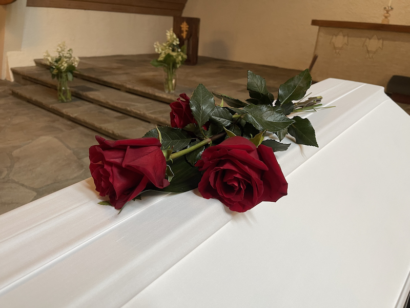 Elokuun opit ja flopit. Kuvassa valkoinen arkku, jonka päällä on kolme punaista ruusua.