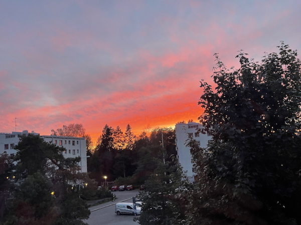 Kovan viikon ilta. Kuvassa iltaruskoinen taivas joka näkyy kerrostalojen välistä.