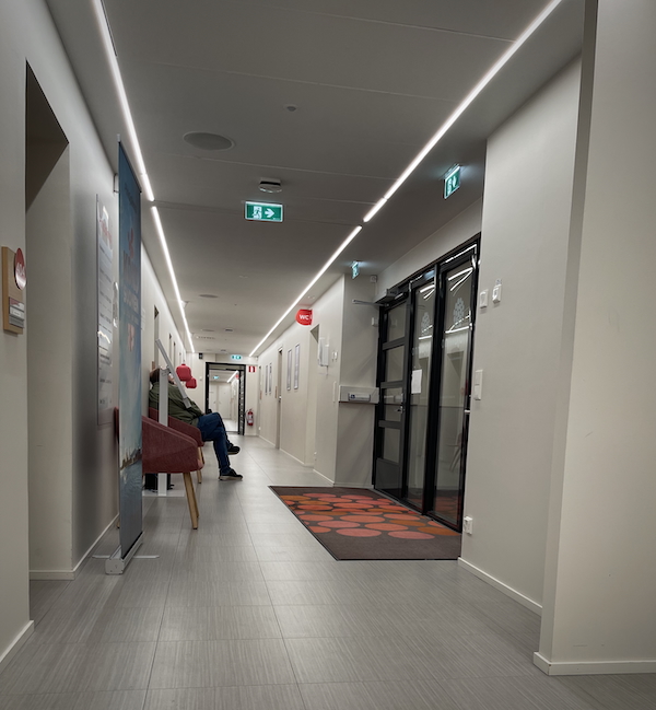 Lokakuun valoja ja varjoja. Kuvassa lääkräikeskuksen käytävä, jolla istuu tuolilla ihminen. 