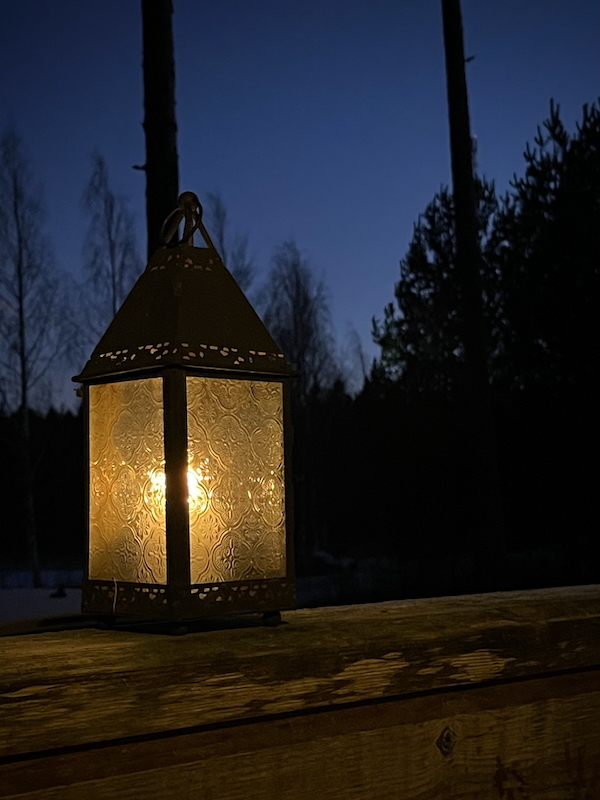 Tajunnanvirtaa vuoden lopulla. Kuvassa kynttilälyhty pimeää taivasta vasten.