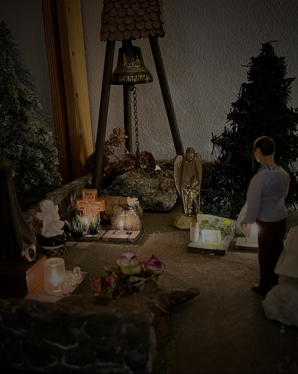 Pyhäinpäivänä. Kuvassa miniatyyrihautausmaa, jossa kynttilät loistavat pikkuhaudoilla. 