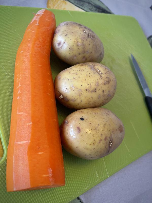 Iso porkkana ja kolme perunaa leikkuulaudalla